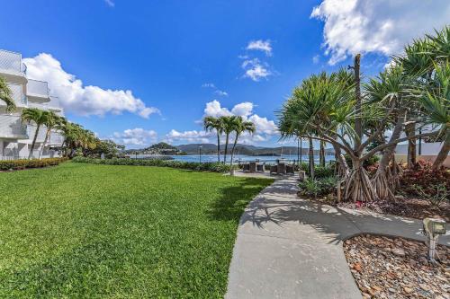 a walkway next to a lawn with palm trees at By The Sea Shore With Pool in Airlie Beach
