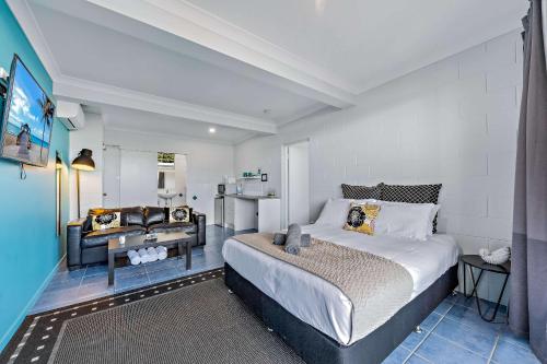 a bedroom with a king sized bed and a couch at Airlie Sun & Sand Accommodation #2 KIDS STAY FREE in Airlie Beach