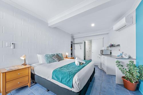 a bedroom with a large bed and a kitchen at Airlie Sun & Sand Accommodation Studio #1 KIDS STAY FREE in Airlie Beach