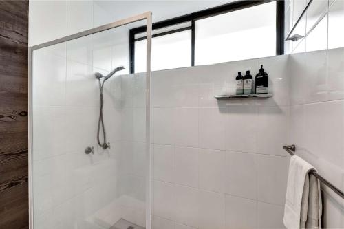 a white bathroom with a shower with a glass door at OCEAN VIEWS 16 pool & Spa Wi-FI in Airlie Beach