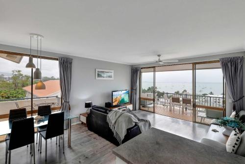 a living room with a couch and a table with a television at OCEAN VIEWS 16 pool & Spa Wi-FI in Airlie Beach