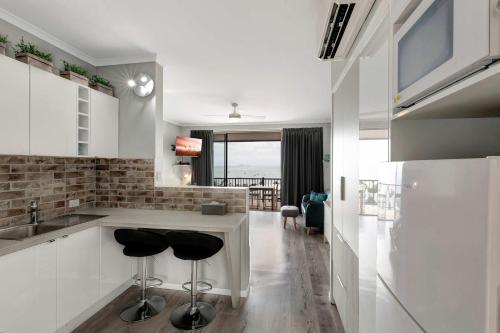 a kitchen with a counter and two stools in it at Ocean View 16A Studio Pool & Spa Wi-Fi in Airlie Beach