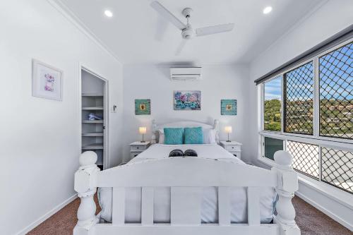 una camera bianca con un letto bianco e due finestre di Seascape Whitsundays ad Airlie Beach