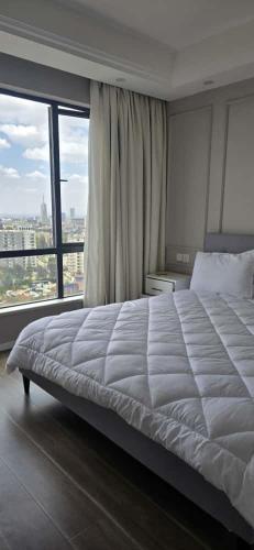a bedroom with a large bed and a large window at Alba Gardens in Gatunga