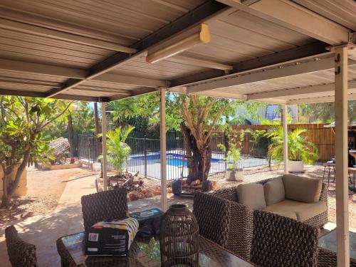 a patio with a couch and chairs under a pergola at 16 Stokes-Hughes Street - With Pool in Exmouth