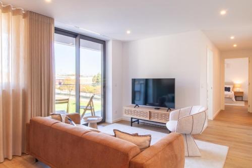 a living room with a couch and a flat screen tv at Stylish 2BR in Leça with AC by LovelyStay in Leça da Palmeira