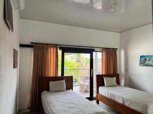 zwei Betten in einem Zimmer mit Fenster in der Unterkunft Dhita Dive Bungalow in Ambat