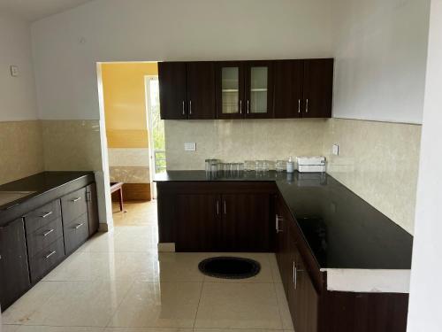 Una cocina con gabinetes negros y una encimera negra. en Hideout nest, en Ooty