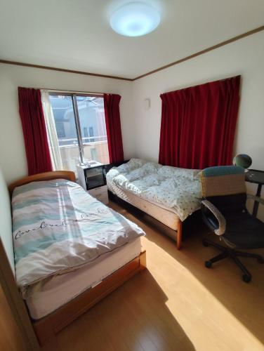 a bedroom with two beds and a chair and a window at 関東最大のスパが身近にあり二部 in Niizo
