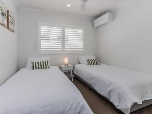 due letti in una stanza bianca con una finestra di Dianella Dunes a Casuarina
