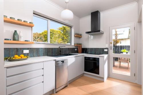 a white kitchen with a sink and a dishwasher at Nelson Bridge House in Nelson