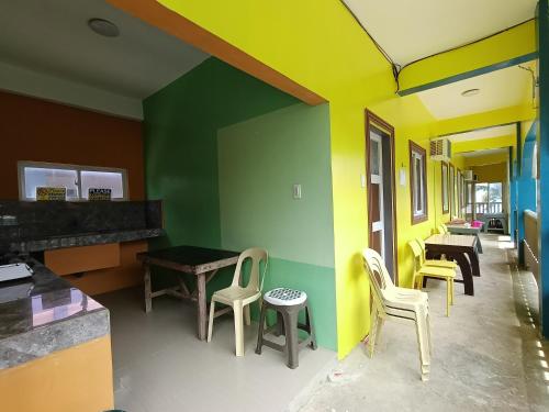 Una habitación con paredes y sillas amarillas y verdes. en Glenmark's Homestay New Oceanview Rooms, en Pagudpud
