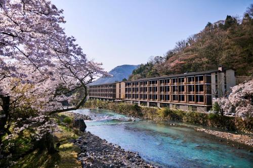 a building on a bridge over a river with pink flowers at Hotel Indigo Hakone Gora by IHG in Hakone