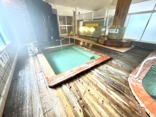 a swimming pool in a building with a wooden floor at Suzuki Ryokan in Noboribetsu