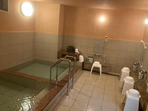 une salle de bains avec une baignoire et trois toilettes dans l'établissement Nobeoka Urban Hotel, à Nobeoka