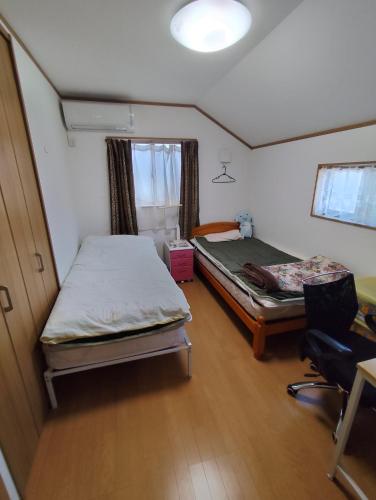 une petite chambre avec deux lits et une chaise dans l'établissement 一軒屋の個室を格安で利用可能, à Niizo