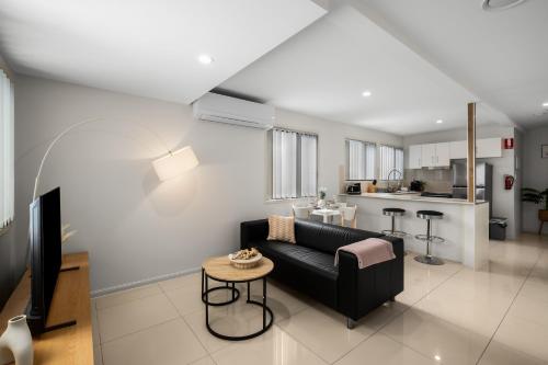 a living room with a black couch and a kitchen at Smart Suites Self Check-in Apartments - Sunnybank Station in Brisbane