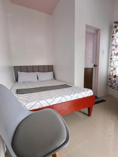 a bedroom with a bed and a chair in it at Glenmark's Homestay in Pagudpud