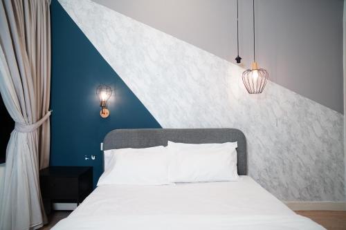 a bedroom with a white bed with a blue wall at Arte Plus Luxury Suites with KLCC View in Kuala Lumpur