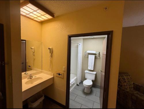 a bathroom with a toilet and a sink and a mirror at Coratel Inn and Suites By Jasper Wichita North in Wichita