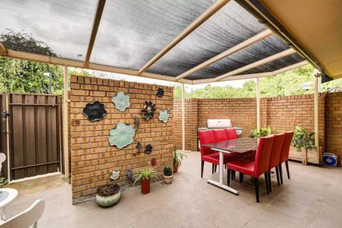 eine Terrasse mit einer Backsteinmauer und einem Tisch mit Stühlen in der Unterkunft Unley rd parkside Adelaide in Unley