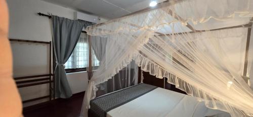 阿努拉德普勒Nature's Touch Villa的卧室里有一张带白色窗帘的四柱床