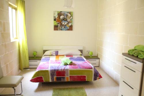 a bedroom with a bed with a quilt on it at Serenity - Bellevue Gozo in Xlendi