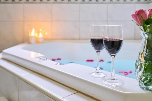 - deux verres de vin rouge assis sur une baignoire dans l'établissement Sanctuary House Resort Motel, à Healesville