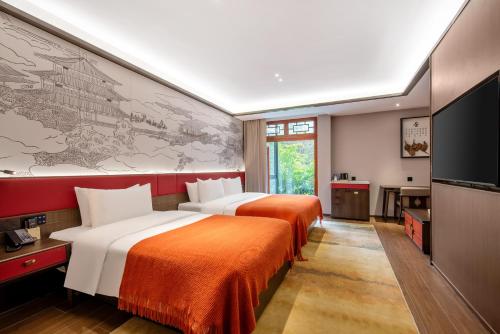a hotel room with two beds and a flat screen tv at Xi'an Jinshengdi Hotel, Datang Everbright City, Big Wild Goose Pagoda Branch in Xi'an