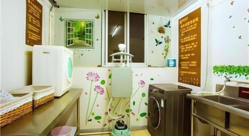 une cuisine avec une machine à laver avec des fleurs sur le mur dans l'établissement JTOUR Inn Wuzhou Arcade City Sanzongfu, à Wuzhou