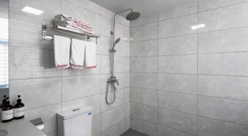 une salle de bain blanche avec douche et toilettes dans l'établissement Shell Hotel Zaozhuang Xinchang Road Bada Market, à Zhaozhuang