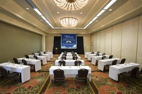 a room with white tables and chairs and a chandelier at Airtel Plaza Hotel in Van Nuys