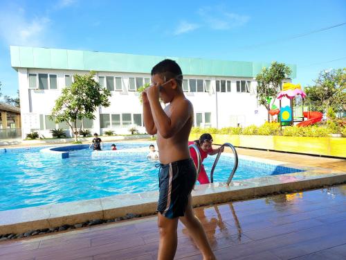 头顿Resort Aria Vũng tàu的一个小男孩在游泳池边用手机打电话