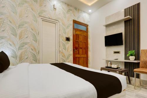 a bedroom with a white bed and a television at Super Townhouse Vishwanath Temple Varanasi in Varanasi