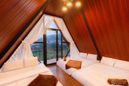 迪昂Dieng Ceria Resort的房间里有两张白色沙发，旁边是一扇大窗户。