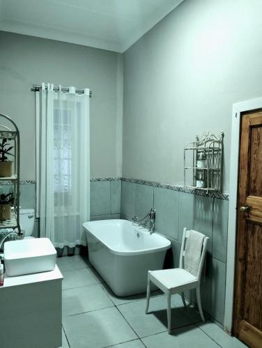 a white bathroom with a tub and a chair at Splash 9 in Trompsburg