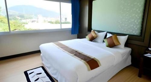 a bedroom with a large white bed with a large window at Piyaporn Hill Paradise Hotel in Mae Sai
