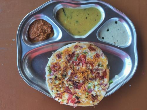 オーロヴィルにあるWoodPacker Hostel Pondicherryのピザとディップとソースが添えられた料理の皿