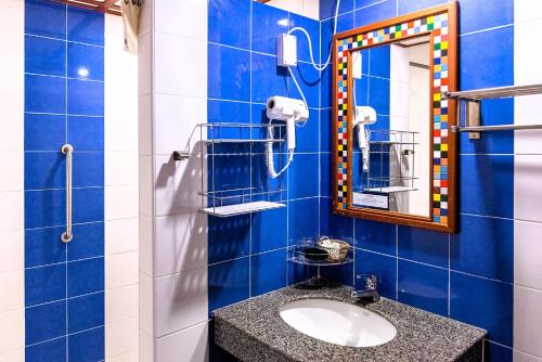 La salle de bains est pourvue de carrelage bleu, d'un lavabo et d'un miroir. dans l'établissement Hua Hin Loft, à Hua Hin
