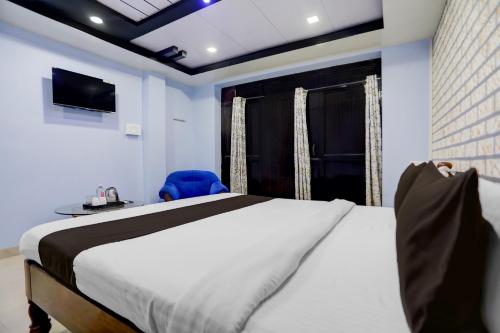 Un dormitorio con una cama grande y una silla azul. en Super Hotel O Hanuman Nagar Kankarbagh Formerly Home Town, en Bankipur