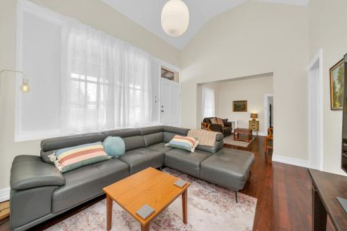 a living room with a leather couch and a table at Bassett Cottage- Heritage Listed- with 3 bedrooms- close to train and shops 