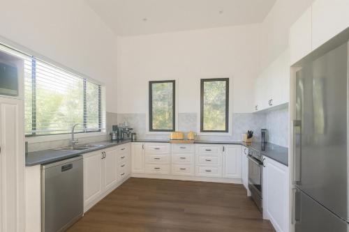 Hibiscus Haven 1BR getaway in Valla Beach في Valla Beach: مطبخ مع دواليب بيضاء واجهزة ستانلس ستيل