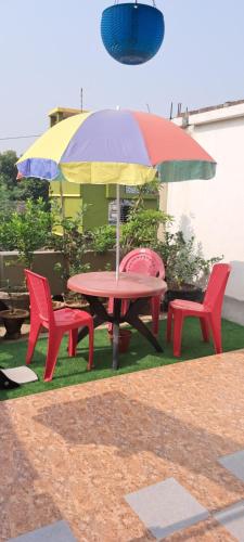 ein Picknicktisch mit zwei Stühlen und einem Sonnenschirm in der Unterkunft Diya STAYS in Rāmpur Hāt