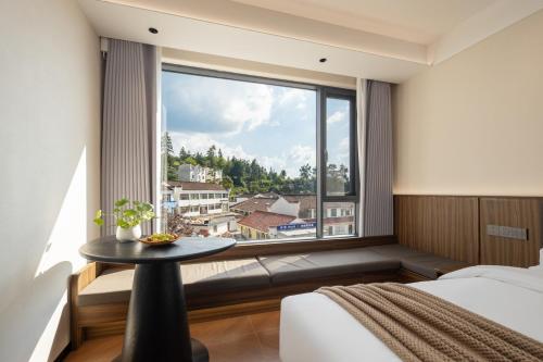 a bedroom with a large window with a table at Jiuhua Goodstay Inn in Chizhou