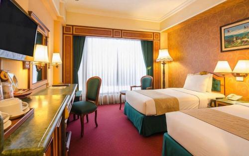 ein Hotelzimmer mit zwei Betten und einem Schreibtisch in der Unterkunft Gajahmada Graha Hotel in Malang