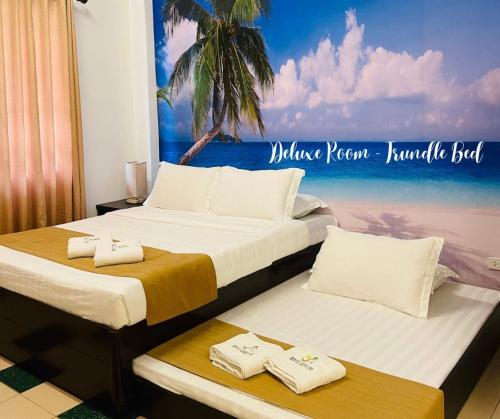 two beds in a room with a picture of a beach at Castle Rock Boracay in Boracay
