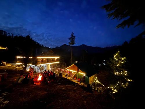un grupo de personas sentadas alrededor de una mesa por la noche en Oreos cafe and stay shangarh, en Shangarh