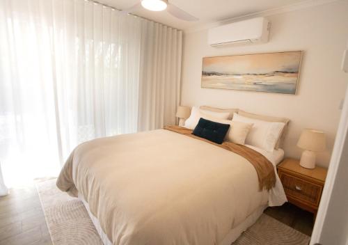 una camera da letto con un grande letto bianco e una finestra di Coastal Courtyard Retreat Jasmine Hideaway Sunshine Coast a Kawana Waters