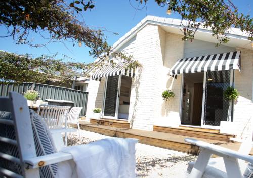 a patio with white chairs and a house at Jasmine Hideaway Guesthouse Near SCUH Hospital in Kawana Waters