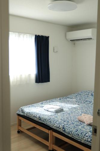 a bed in a room with a window at 海に近い田舎にある新築家の丹霞阁 in Itoman